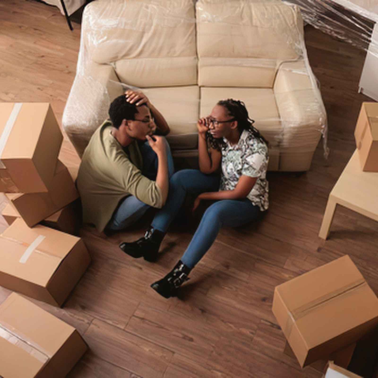Stress du déménagement : couple assis au milieu des cartons dans un appartement vide